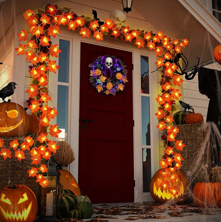 Halloween-themed outdoor decoration with lights, pumpkins, and a wreath on a door.